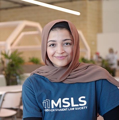 Image of Zahra sitting in a cafe smiling at the camera